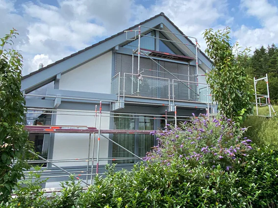 Einfamilienhaus mit Photovoltaik im Gerüst während der Fassadenarbeiten