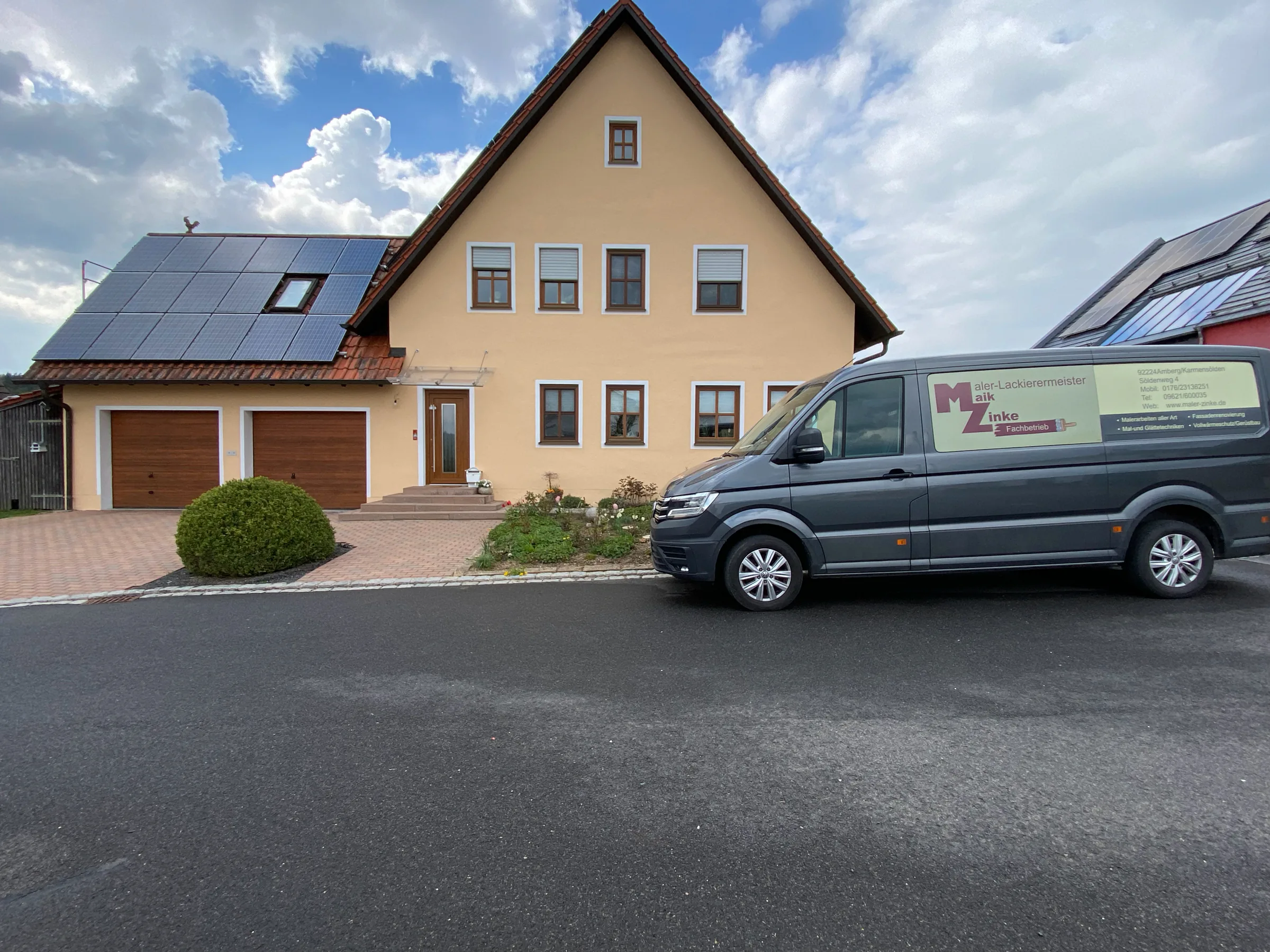 Frisch gestrichenes Bauernhaus mit cremefarbener Fassade und Solardach, davor der Firmenwagen von Malerfachbetrieb Maik Zinke