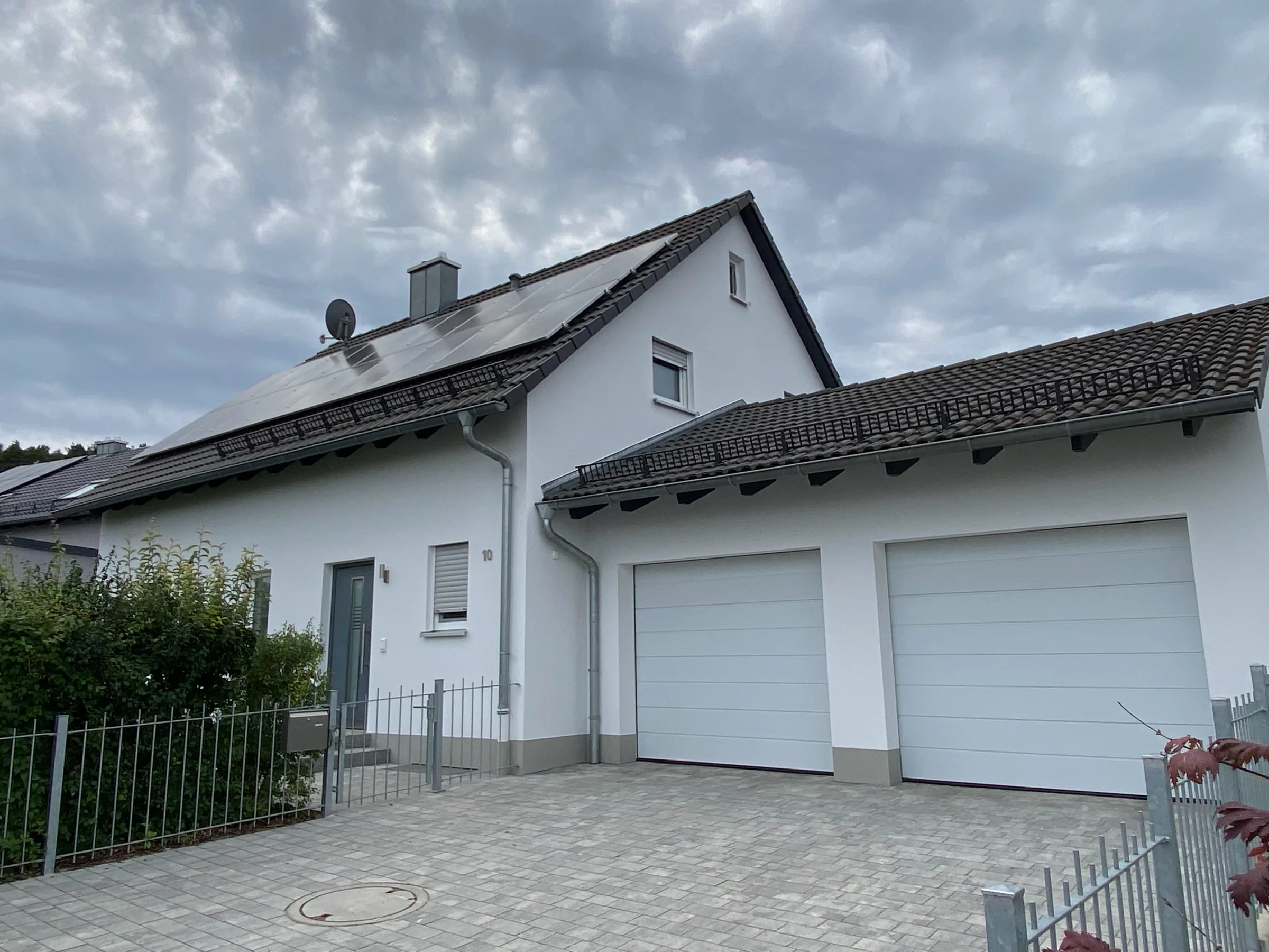 Weiß gestrichenes Einfamilienhaus mit Doppelgarage und Photovoltaikanlage nach dem Fassadenanstrich