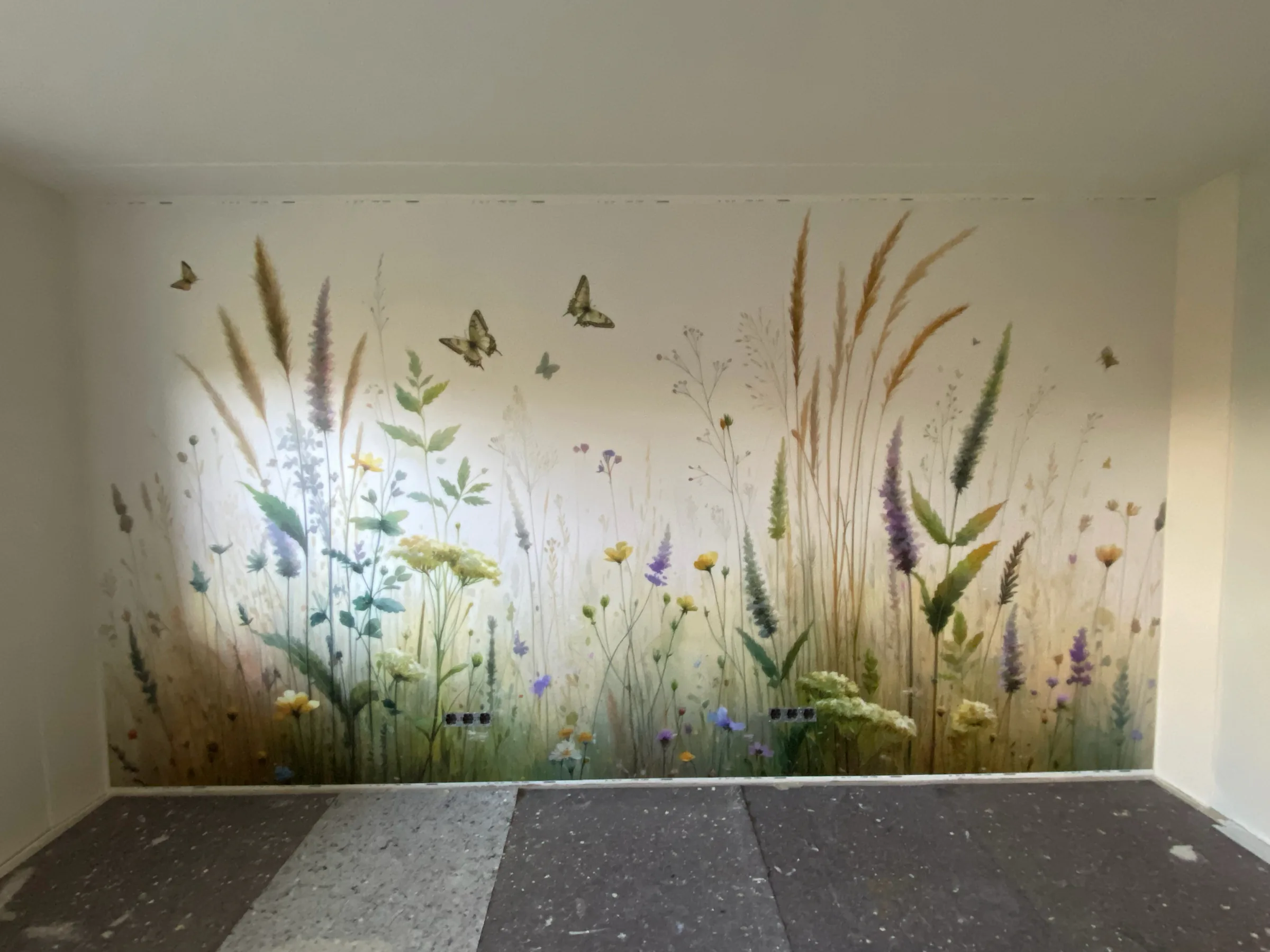Wohnraum mit großflächig verlegter Fototapete: eine Wildblumenwiese mit Schmetterlingen über die gesamte Wandbreite
